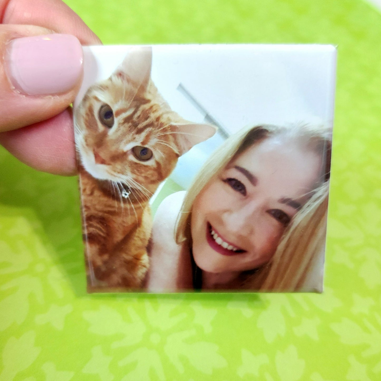 Small photo magnet with a cat and a person on a green background