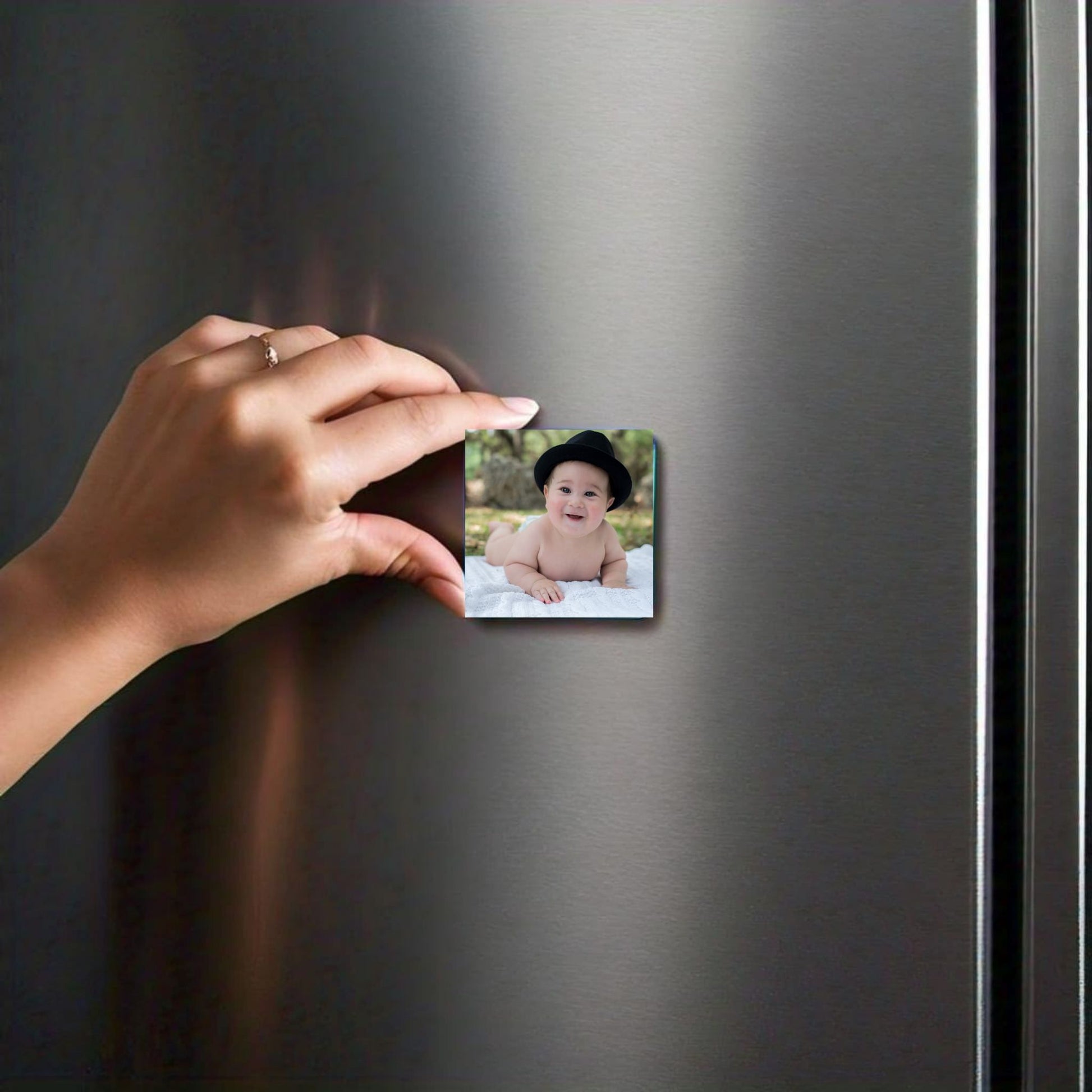 hand holding magnet of baby infront of refrigerator door