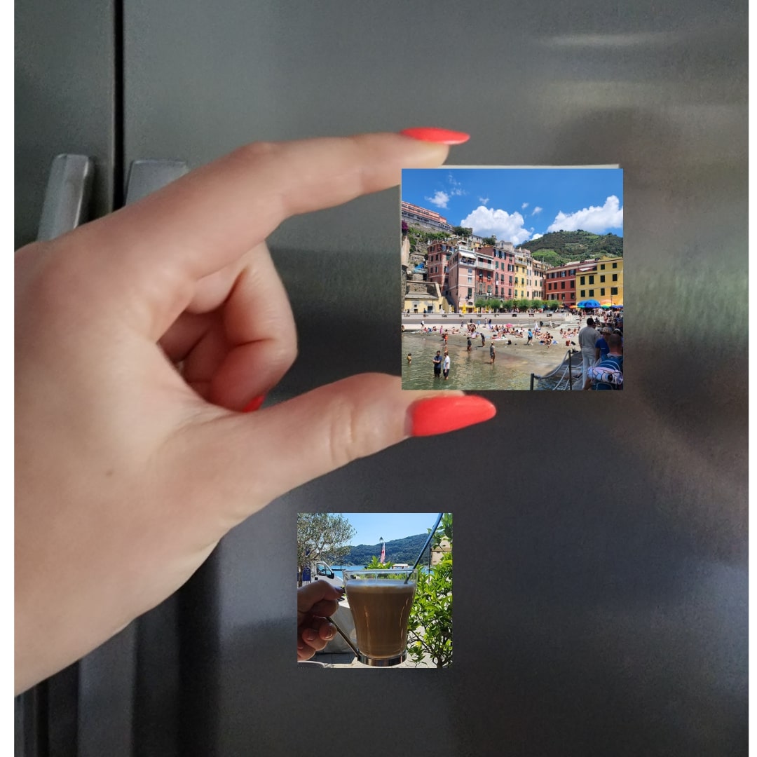 hand holding photo magnet of Italy in front of fridge door